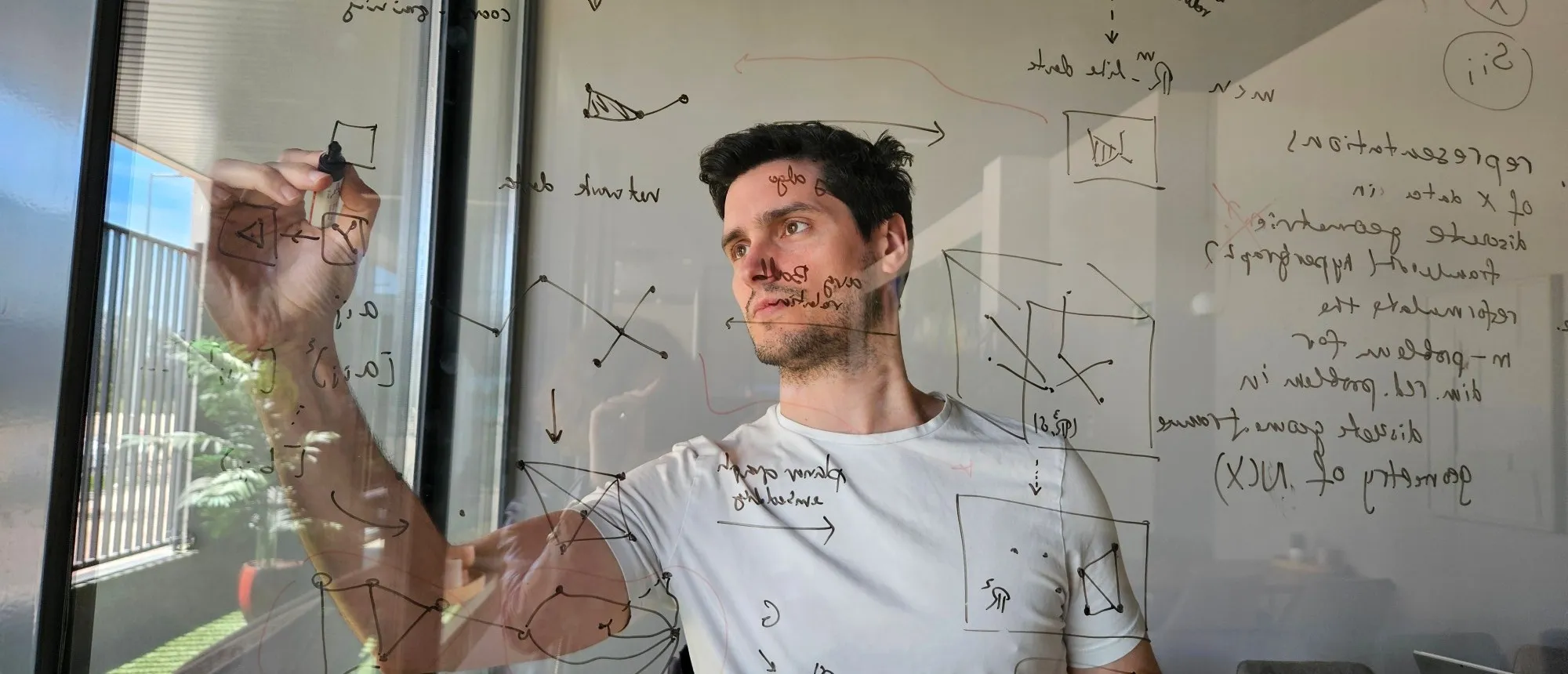Carlos sketching hypergraph diagrams on a glass board