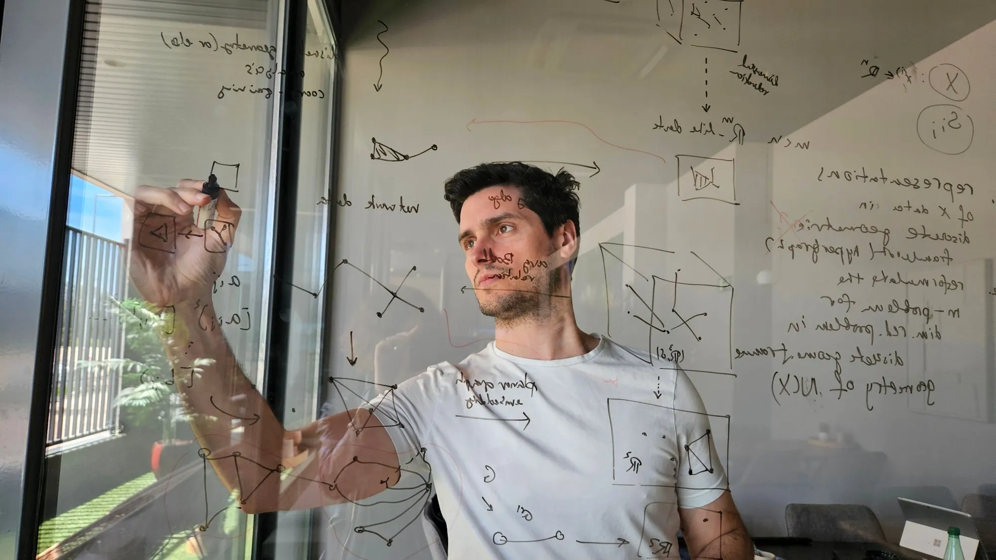Carlos working through hypergraph diagrams on a glass board
